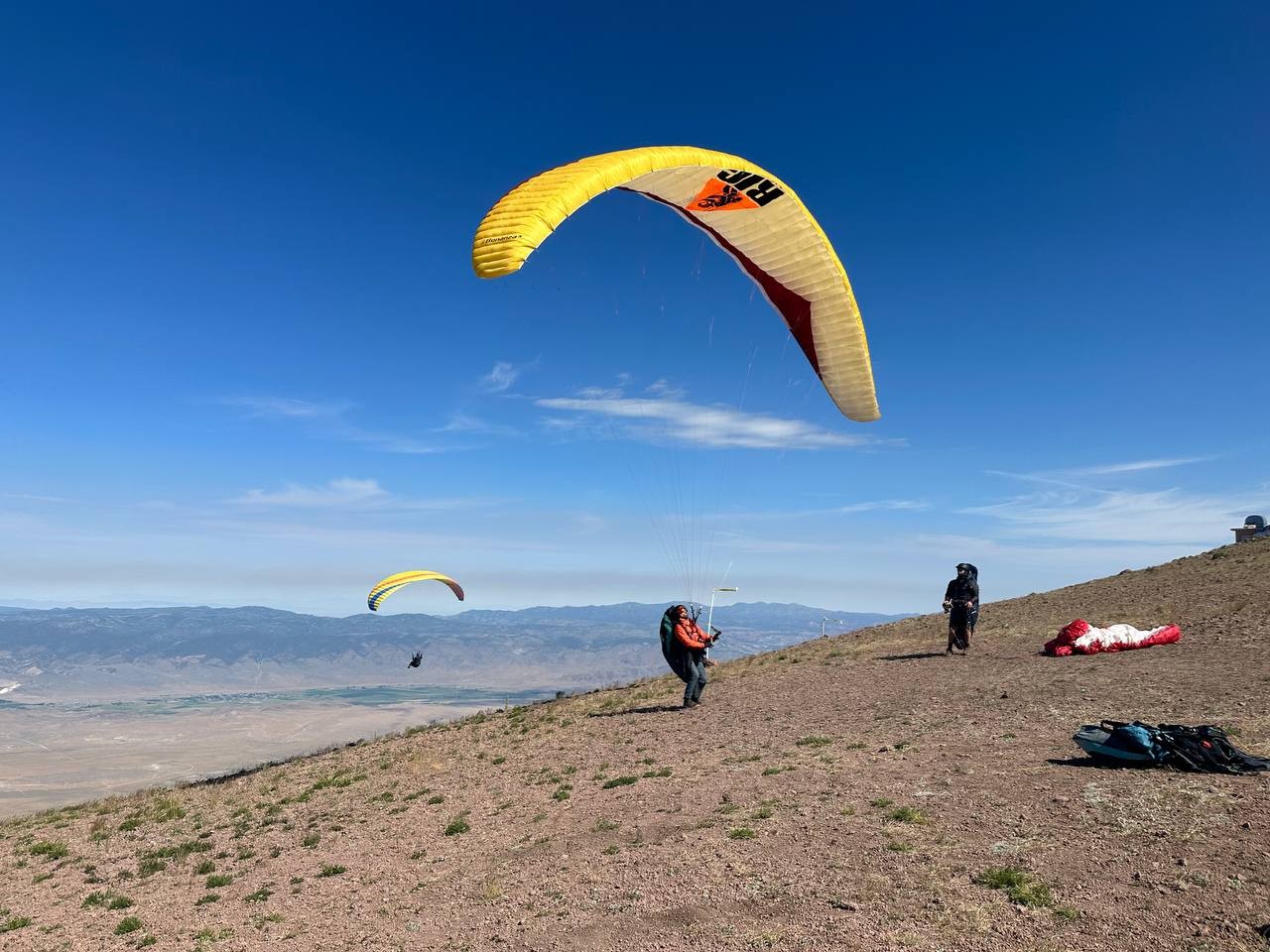 Paraglider launching with a yellow and red wing in Monroe, Utah